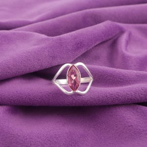 Könnte beinhalten: Ein silberner Ring mit einem filigranen durchbrochenen Design, das mit einem rosafarbenen, markisenförmigen Edelstein verziert ist.