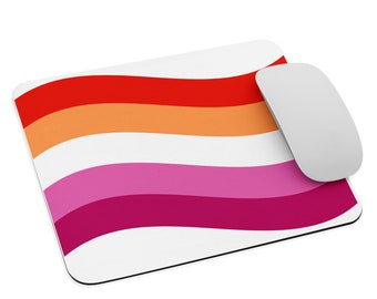 Puede incluir: Alfombrilla de ratón rectangular con el diseño de la bandera del orgullo lésbico. La bandera consta de seis franjas horizontales en tonos rojo, naranja, naranja claro, rosa, magenta y magenta oscuro. Un ratón inalámbrico blanco está a la derecha.