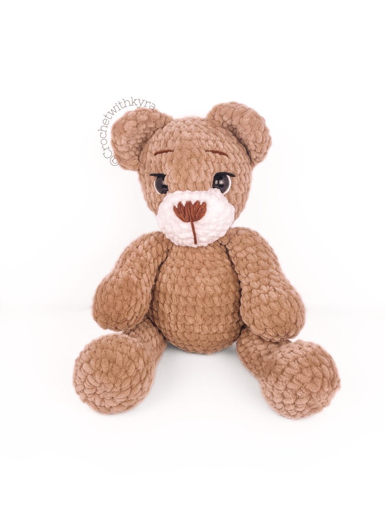 Peut inclure: Un ours en peluche crochet&eacute; marron avec du fil blanc pour le nez et des yeux en boutons noirs. L'ours est assis les jambes &eacute;cart&eacute;es.