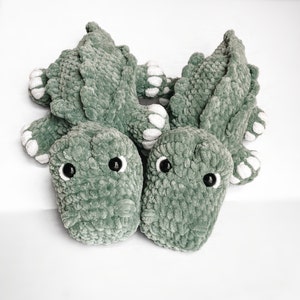 May include: Three crocheted green alligator plush toys with white felt accents and black button eyes.