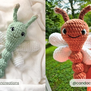 May include: Two crocheted dragonfly plush toys made of soft yarn. One is light green with white wings and the text indigoanncreations, the other is rust orange with white wings and the text candace_crochets. Both have black eyes and antennae.