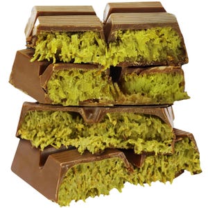 May include: A stack of chocolate bars with a light brown exterior and a bright green, textured filling. The bars are broken, revealing the filling. The image is a close-up, highlighting the texture and color contrast.