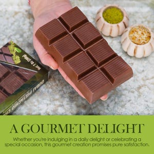 May include: A large, rectangular chocolate bar with scored sections is held in a hand. The bar is a rich brown color. The packaging is visible, with the text "DUBAI PISTACHIO CHO" and "Net 7 Oz (200g)". The image also includes the text "A GOURMET DELIGHT".