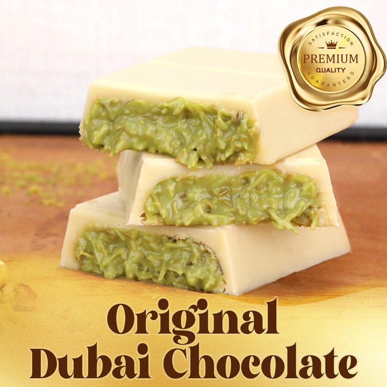 May include: Three stacked pieces of white chocolate with a green filling. The image includes a gold seal that says "Premium Quality". The text "Original Dubai Chocolate" is at the bottom of the image.
