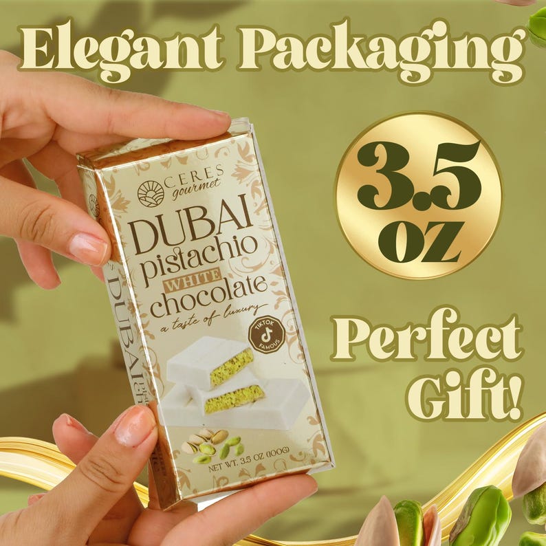 May include: A gold and white box of Dubai pistachio white chocolate, with the text "Dubai Pistachio White Chocolate" and "3.5 OZ". The packaging is held by a person's hands. The image also includes the text "Elegant Packaging" and "Perfect Gift!"