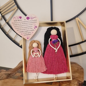May include: A framed handmade craft with two yarn dolls. The dolls are holding hearts and flowers. The frame is gold and the dolls are pink and red. The background is a wooden surface. The text on the heart reads "Dear Mum, Thank you for everything, for the kindest things you do. Thank you for being there and putting me in front of you. Thank you for supporting me and showing me the way. I wish I said it more. I love you everyday!"