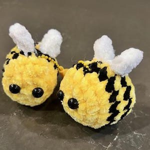 Può includere: Due ornamenti a forma di ape in peluche fatti a mano. Le api sono gialle con strisce nere e occhi di perline nere. Ogni ape ha due antenne bianche e soffici. Gli ornamenti sono progettati per assomigliare ad api.