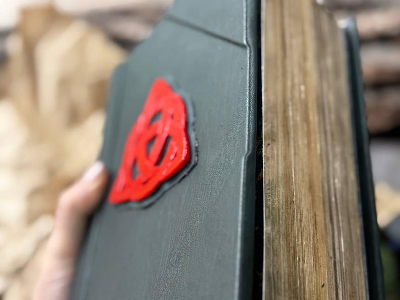 May include: A dark green hardcover book with a red, three-dimensional, Celtic knot design on the front cover.