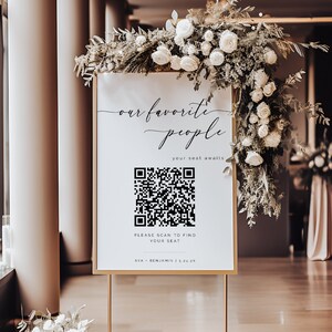以下が含まれることがあります： 金色の枠と花で飾られた白い看板。看板には「our favorite people」と書かれており、QRコードには「席を探すにはスキャンしてください」と「AVA + BENJAMIN 1.5.24 24」の文字が書かれています。