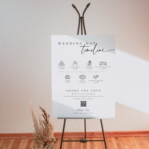 May include: A white wedding day timeline sign with black text and icons. The sign lists the wedding day events with times, including the ceremony, cocktail hour, dinner, and send-off. The sign also includes a QR code for guests to share their photos.