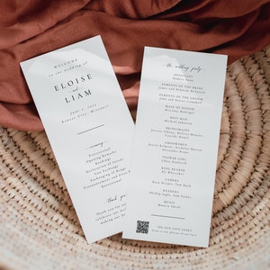 May include: Two white cards with black text. The left card says "Welcome to the wedding of Eloise and Liam" with the date and location. The right card lists the wedding party with the officiant, parents of the bride and groom, maid of honor, best man, bridesmaids, groomsmen, flower girl, ring bearer, ushers, readers, music, and a QR code that says "See our love story".