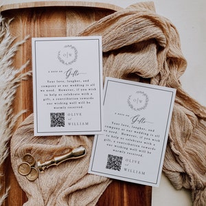 Op de afbeelding: Twee witte kaarten met zwarte randen en een eenvoudig ontwerp. De kaarten hebben een zwart-wit monogram met de letters "O" en "W" omringd door een krans. De tekst op de kaarten luidt "a note on Gifts" en "Your love, laughter, and company at our wedding is all we need. However, if you wish to help us celebrate with a gift, a contribution towards our wishing well will be warmly received. OLIVE and WILLIAM". Een QR-code bevindt zich onderaan elke kaart.