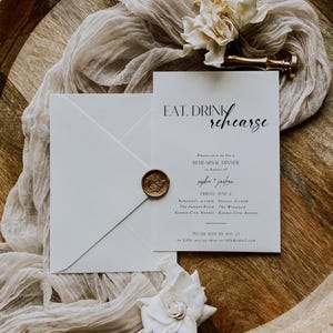 Può includere: Un invito bianco con testo nero che recita "EAT. DRINK. rehearse" e "Please join us for a REHEARSAL DINNER in honor of sophie + jaegson FRIDAY, JUNE 6 Rehearsal, 4:00pm Dinner, 6:00pm The Sawyer Room The Winstead Kansas City, Kansas Kansas City, Kansas PLEASE RSVP BY MAY 23 to Lilly, 913-555-0000 or lilly@email.com". La carta è su una superficie di legno con una busta bianca e un sigillo di cera.