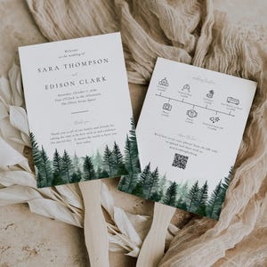 May include: Wedding ceremony program fans with a watercolor forest design. The fans feature the names Sara Thompson and Edison Clark, the wedding date, and the ceremony location. The back of the fan includes a wedding timeline and a QR code.