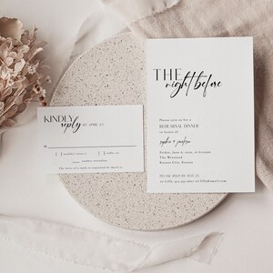 Op de afbeelding: Een witte RSVP-kaart met zwarte tekst. De kaart zegt "Kindly reply by April 23". Er zijn selectievakjes voor "I wouldn't miss it", "Sadly, no" en een regel voor het aantal deelnemers. De tekst "The favour of a reply is requested by April 23" staat onderaan de kaart. De kaart ligt naast een witte uitnodigingskaart met zwarte tekst. De uitnodigingskaart zegt "The night before" in een handschrift. De tekst "Please join us for a rehearsal dinner in honour of Sophie + Jackson" staat onder de titel. De uitnodigingskaart bevat ook de datum, tijd, locatie en RSVP-informatie.