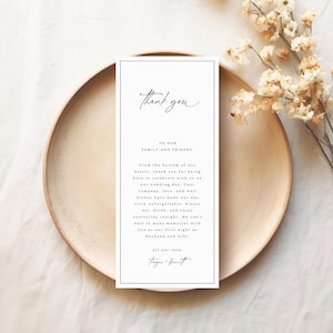 May include: A white thank you card with black calligraphy text. The card reads "Thank you" at the top and "To our family and friends. From the bottom of our hearts, thank you for being here to celebrate with us on our wedding day. Your company, love, and well wishes have made our day truly unforgettable. Please eat, drink, and enjoy yourselves tonight. We can't wait to make memories with you as our first night as husband and wife. All our love, [signature]"