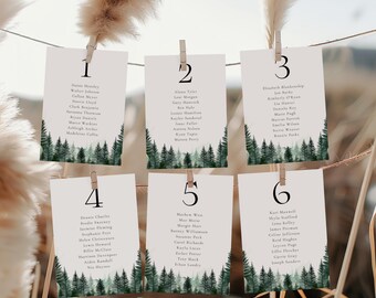 May include: Six white cards with black numbers 1 through 6, each with a list of names and a watercolor illustration of a forest with green trees. The cards are hanging from a string with wooden clothespins.