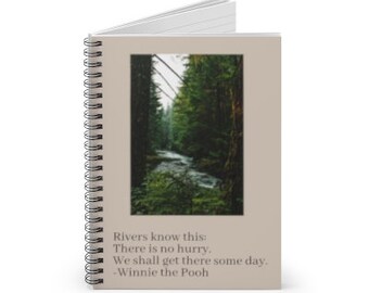 May include: A spiral bound notebook with a beige cover featuring a photograph of a forest path with a stream running through it. The quote "Rivers know this: There is no hurry. We shall get there some day. - Winnie the Pooh" is printed below the image.