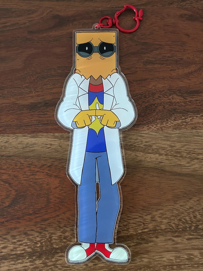K&ouml;nnte beinhalten: Ein klarer Acryl-Anh&auml;nger mit einer Cartoon-Figur mit Papiert&uuml;tenkopf, Sonnenbrille und wei&szlig;em Laborkittel. Die Figur tr&auml;gt ein blaues Hemd, eine blaue Hose und rote Schuhe. Oben ist ein roter Verschluss angebracht.