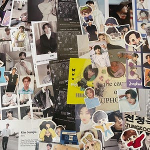 May include: A collection of BTS merchandise, including photo cards, stickers, and small prints. The images feature various members of the K-pop group, with some items displaying text like "Jungkook" and "Kim Seokjin."