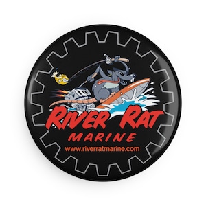 May include: A black and white button with a cartoon rat riding a jet ski and holding a fishing rod. The text "River Rat Marine" is in red and white, with the website address "www.riverratmarine.com" below it.