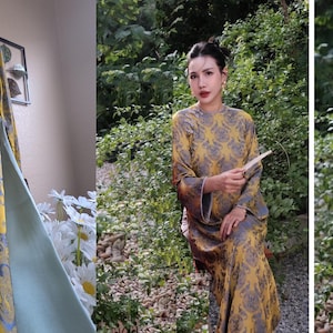May include: A yellow and gray patterned dress with long sleeves and a high collar. The dress is hanging on a hanger and is also being worn by a person. The dress has a floral design and is made of a soft, flowing fabric.