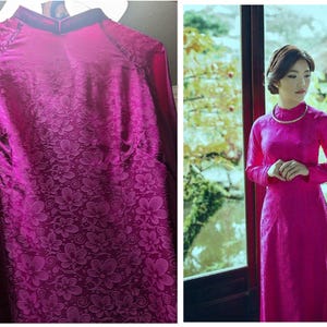 May include: A magenta-colored, long-sleeved dress with a floral pattern. The dress has a mandarin collar and is displayed on a hanger. A person is wearing the dress in a separate image, standing near a window.