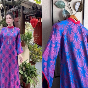May include: A long, flowing dress with a vibrant blue and pink floral pattern. The dress features long sleeves and a mandarin collar with red trim. The fabric has a glossy sheen, and the design is reminiscent of traditional Asian attire.