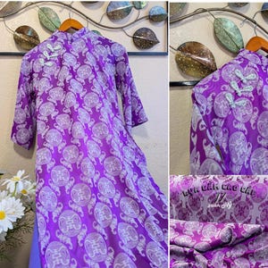 May include: A purple dress with a mandarin collar and three-quarter sleeves. The dress features a white circular pattern and decorative frog closures. The fabric is a vibrant purple with a matching purple lining.