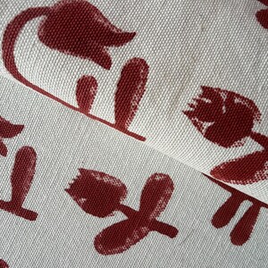 Peut inclure: Gros plan sur un tissu avec un motif répété de fleurs et de tiges marron stylisées sur un fond crème. Le tissu est plié, révélant la texture et le design. Le motif floral rappelle les tulipes.