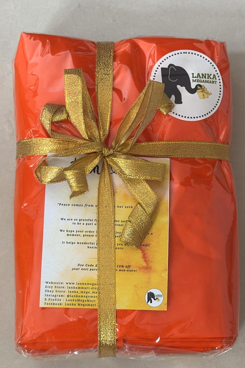 May include: An orange package wrapped in clear cellophane and tied with a gold ribbon and bow. A circular sticker with an elephant logo and text is visible. The package contains a card with text.