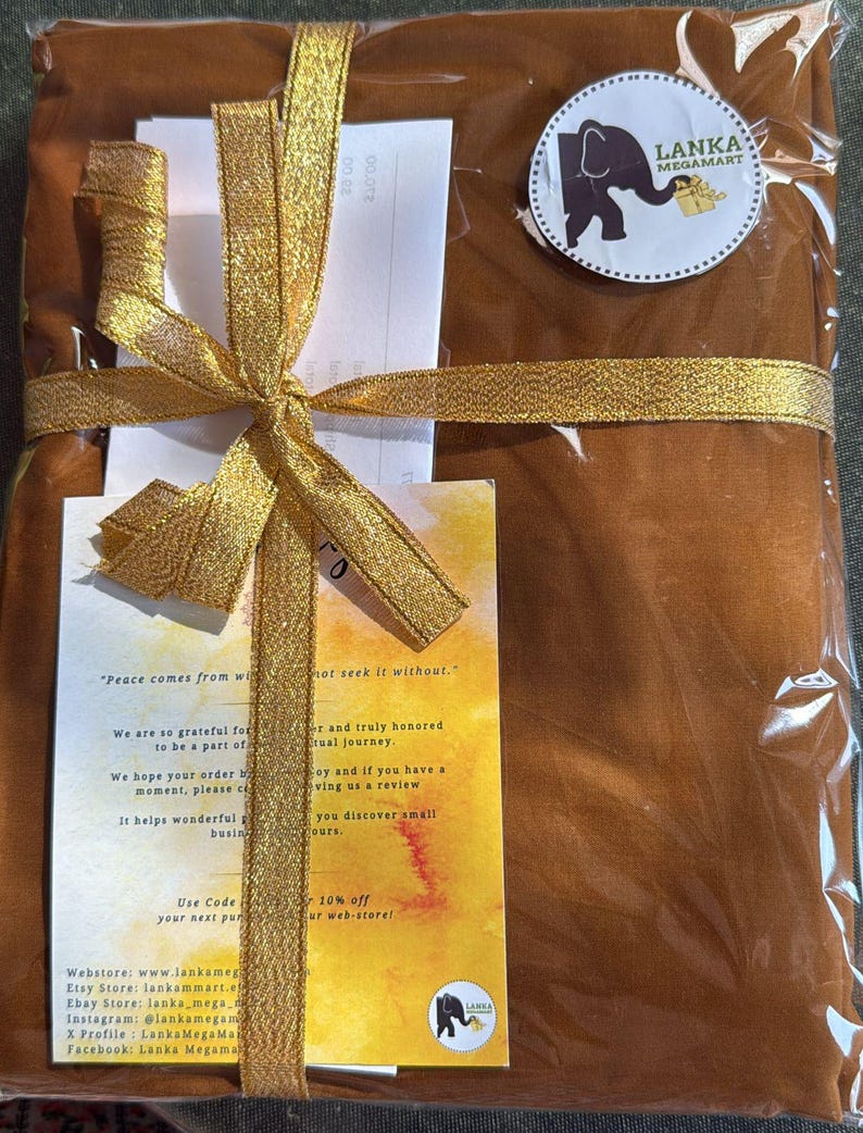May include: A wrapped package in a clear plastic bag, tied with a gold ribbon and bow. The package is a warm brown color. A circular sticker with an elephant logo and text is visible. Includes a handwritten note.