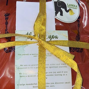 May include: A red gift bag with a gold ribbon tied around it. The bag has a thank you card with the text "You, yourself, as much as your affection." and "We are so grateful and honored to be a part of your spiritual journey. We hope you enjoy our offerings and if you have a moment, consider leaving us a review. It helps wonderful businesses like you discover small businesses like ours."