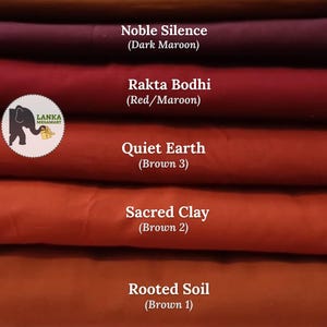 May include: A stack of fabric samples in shades of brown and maroon. The colors are labeled: Bhumi Gold (Mustard Brown), Noble Silence (Dark Maroon), Rakta Bodhi (Red/Maroon), Quiet Earth (Brown 3), Sacred Clay (Brown 2), and Rooted Soil (Brown 1).