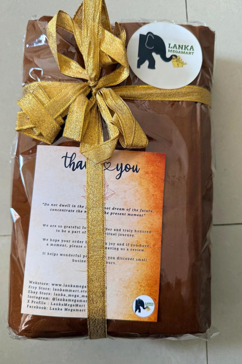 May include: A wrapped gift with a gold ribbon and bow. The gift is brown and has a tag that says "thank you." The tag also has text from the seller, Lanka Megamart, and a logo with an elephant.