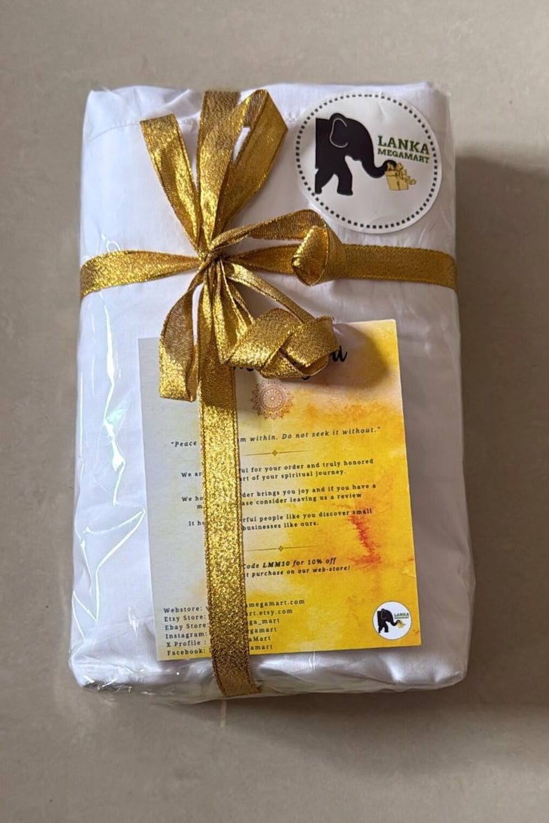 May include: A wrapped package tied with a gold ribbon and bow. A circular sticker with an elephant logo is visible. A small card with text is attached to the package. The package is white.
