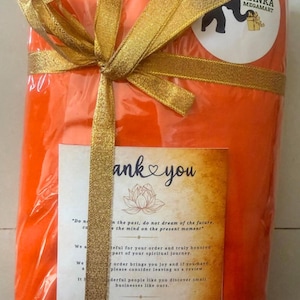 May include: An orange package wrapped in clear plastic and tied with a gold ribbon. A sticker with a black elephant and the text "Lanka Megamart" is on the package. A card with the words "thank you" is also visible.