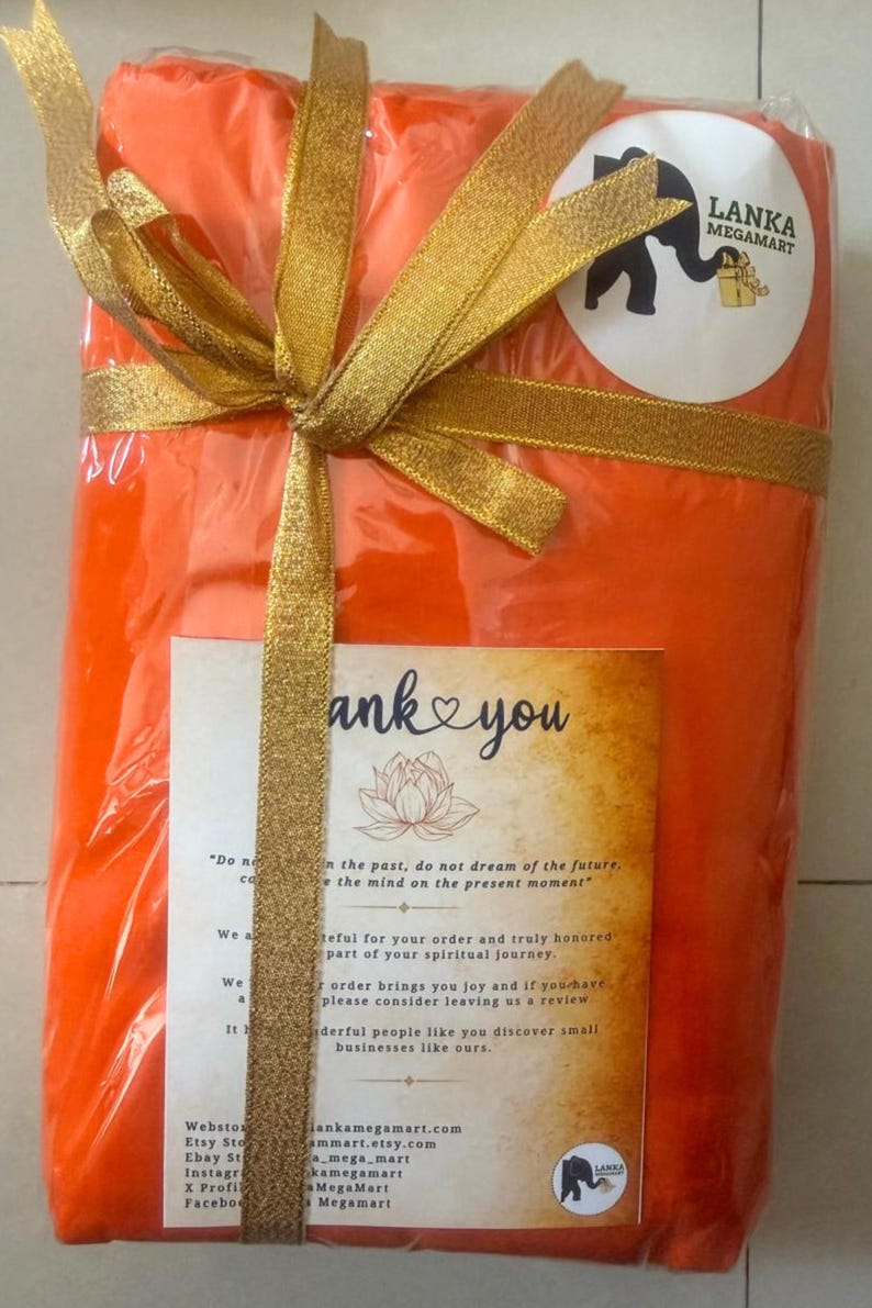 May include: An orange package wrapped in clear plastic and tied with a gold ribbon. A sticker with a black elephant and the text "Lanka Megamart" is on the package. A card with the words "thank you" is also visible.