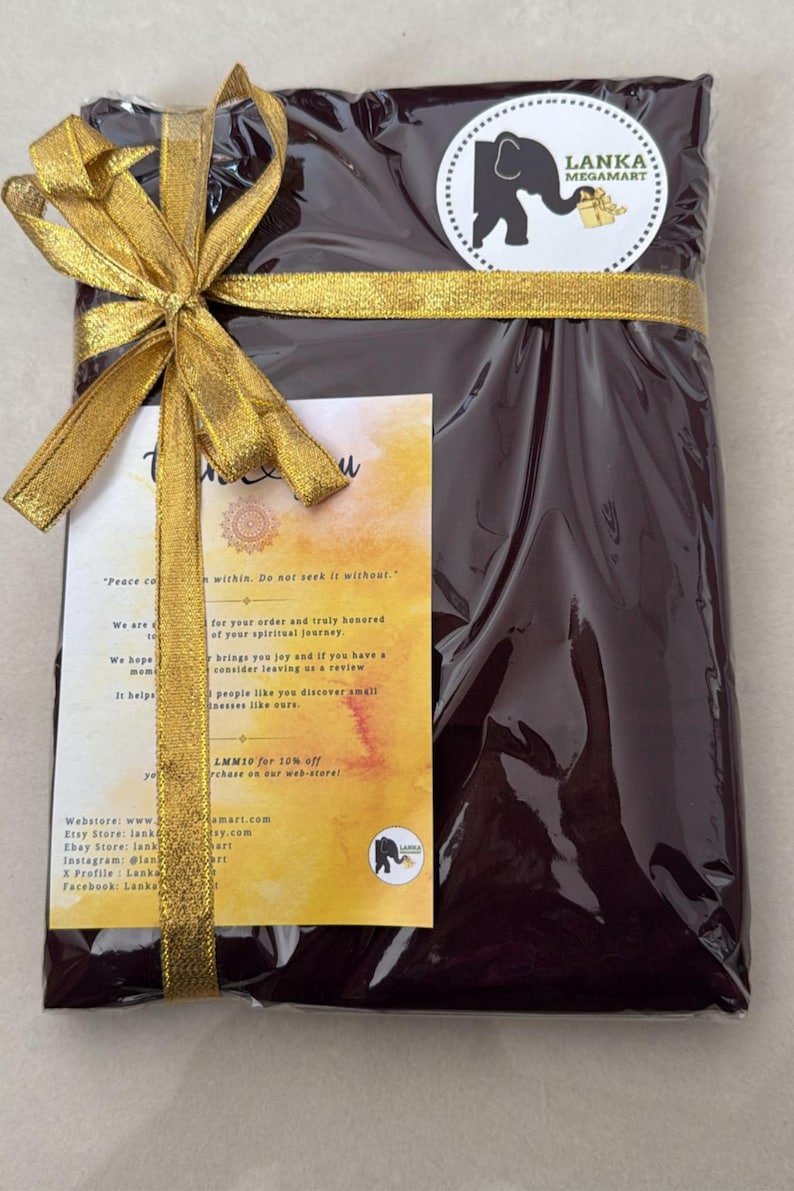 May include: A wrapped package in dark burgundy cellophane, tied with a gold ribbon and bow. A circular sticker with an elephant logo is visible. A small card with text is attached to the package.