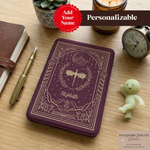 May include: A personalized, dark purple journal with a gold dragon design, the name "Elizabeth", and the words "Add Your Name" and "Personalizable". Other items include a pen, a small clock, and a small figurine.