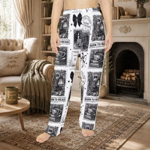 May include: White lounge pants featuring a repeating black and white graphic print of books, teacups, candles, and bows. The pattern includes rectangular frames with text such as "BORN TO READ" and "BOOK BOYFRIENDS" interspersed with small stars and decorative elements.