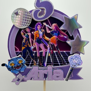 May include: A purple and silver cake topper with the number 5, a disco ball, and three holographic stars. The topper features three animated figures and the name "Aria" in purple letters. A blue cartoon tiger and a light stick are also included.