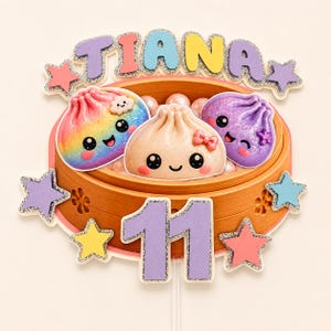 May include: A cake topper featuring a bamboo steamer basket holding three cute dumpling characters with faces. The topper displays the name TIANA in colorful letters, the number 11 in purple, and several glittery stars in various pastel colors.