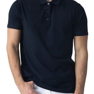 May include: A navy blue polo shirt with short sleeves and a three-button placket. The shirt has a classic collar and is made of a smooth, solid-colored fabric. The shirt is shown on a person.