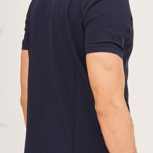 May include: Navy blue polo shirt with short sleeves. The shirt has a classic collar and a buttoned placket. The fabric appears to be a smooth, solid color. The shirt is a casual wear item.