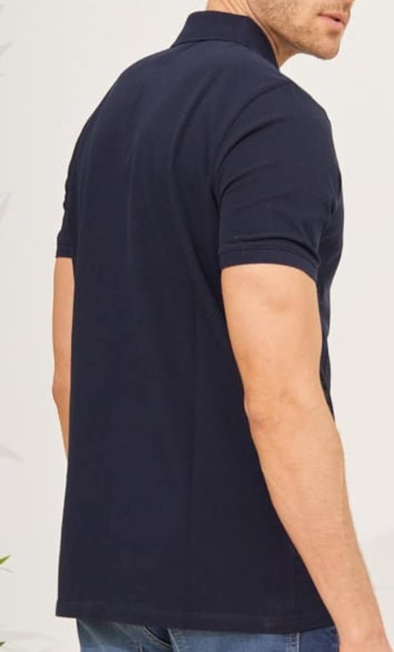 May include: Navy blue polo shirt with short sleeves. The shirt has a classic collar and a buttoned placket. The fabric appears to be a smooth, solid color. The shirt is a casual wear item.