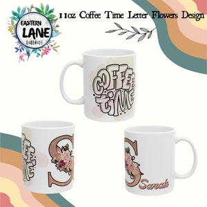Puede incluir: Tres tazas de cerámica blanca con diferentes diseños. La primera taza tiene las palabras "Coffee Time" en letras rosa y negras. La segunda taza tiene una letra "S" de purpurina rosa con flores rosas. La tercera taza tiene una letra "S" de purpurina rosa con flores rosas y el nombre "Sarah" escrito debajo.