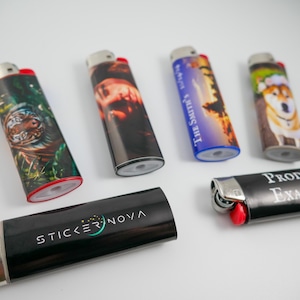 Pu&ograve; includere: Sei accendini rettangolari con vari disegni stampati. Uno raffigura una tigre, uno un ritratto, uno un tramonto con il testo THE SMITH'S, uno un cane, uno il testo STICKER NOVA e uno il testo PRODUCT EXAMPLES. Ognuno ha una parte superiore in metallo.