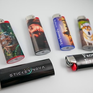 May include: An assortment of lighters with various designs. One lighter features the text "PRODUCT EXAMPLES". Another displays the text "STICKER NOVA". Other lighters have images of a tiger, a sunset, and a dog.