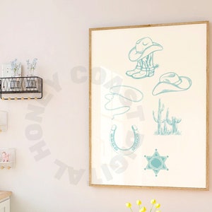 May include: A framed print featuring turquoise cowboy-themed illustrations, including hats, boots, a horseshoe, and a sheriff's badge. The print hangs on a light pink wall above a wooden table with a small orange vase holding yellow flowers.